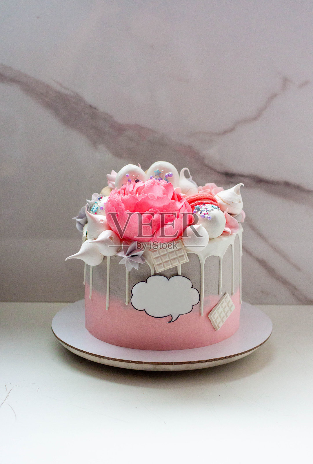 美丽优雅的灰色和粉红色蛋糕，装饰有融化的白巧克力，杏仁饼，可食用的牡丹花和蛋白霜之吻照片摄影图片