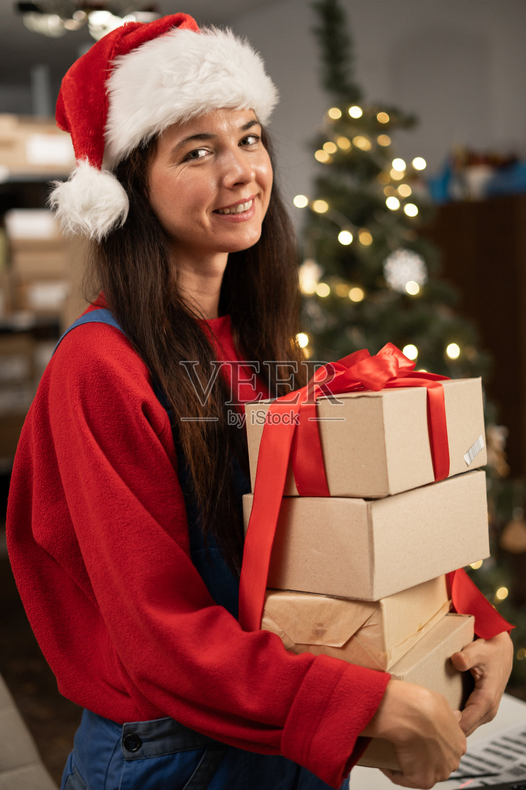 戴着圣诞帽，手捧圣诞礼物的女圣诞老人照片摄影图片