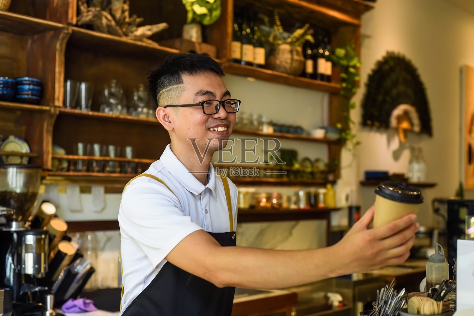 咖啡馆里，越南侍者面带微笑，手里拿着装有咖啡的纸杯照片摄影图片
