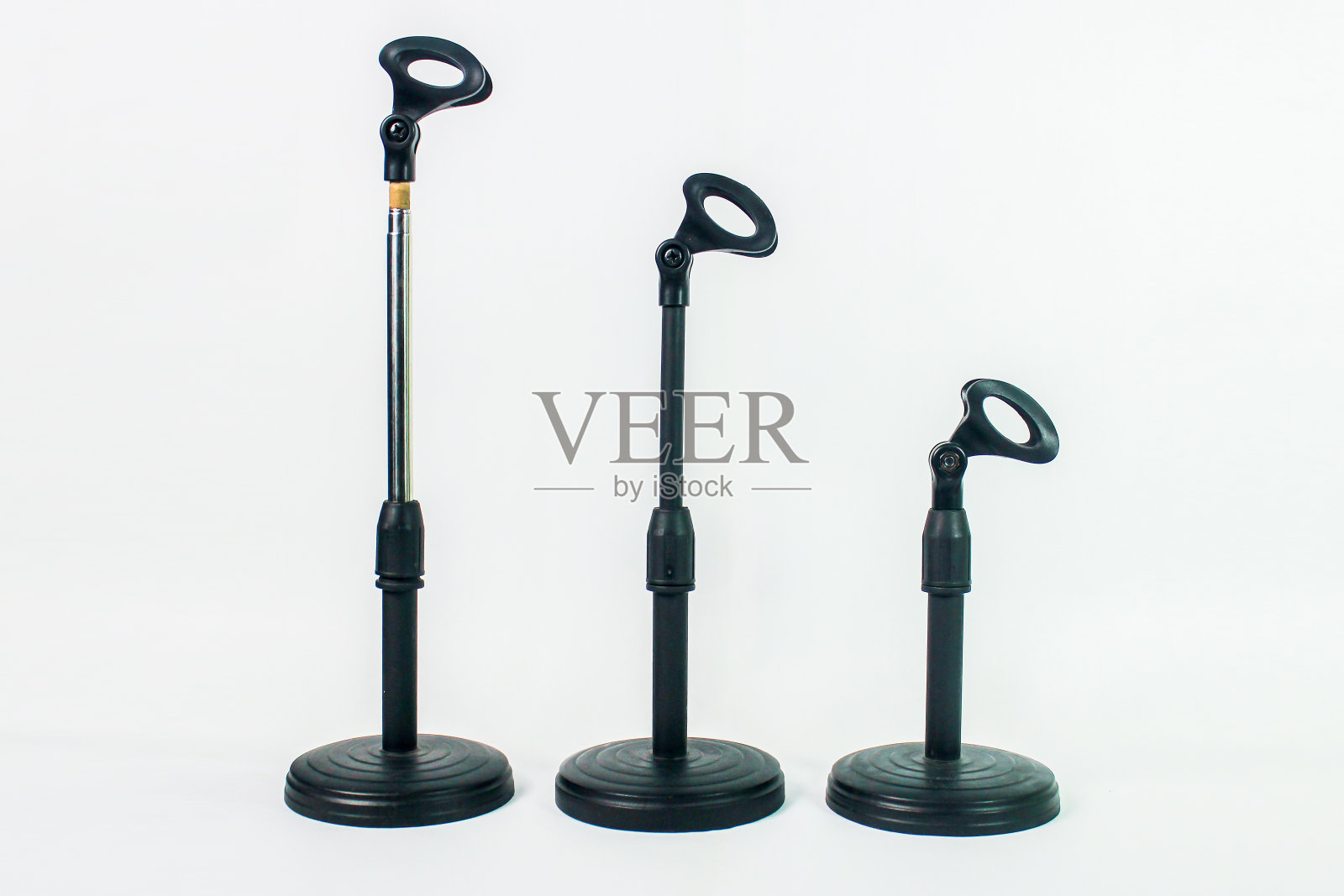 三个白色背景的黑色麦克风支架。播客概念照片摄影图片