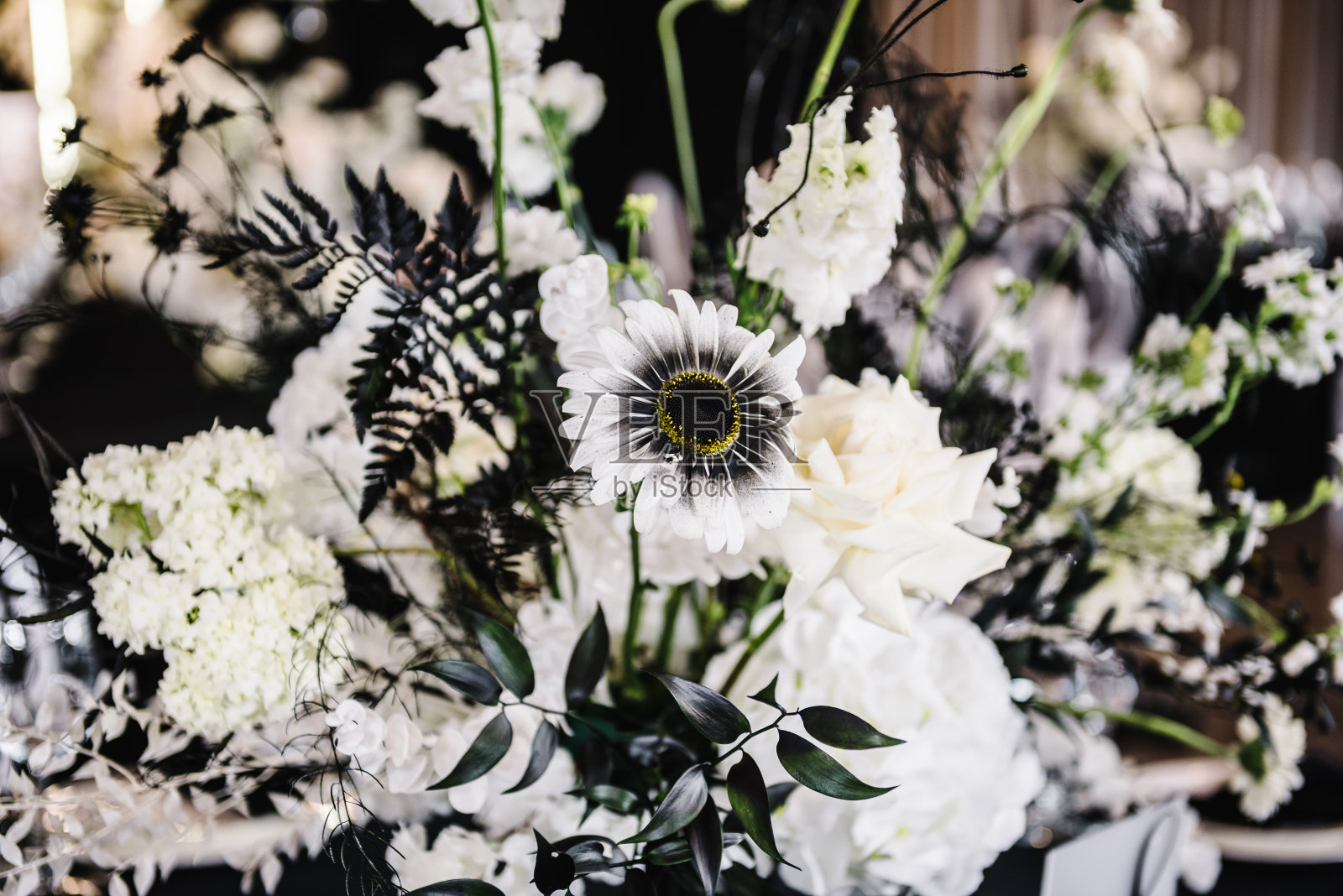 鲜花的背景。花朵构图以玫瑰为主，而绿叶则放在桌子中央。婚礼布置，餐桌接待。装饰细节特写。照片摄影图片