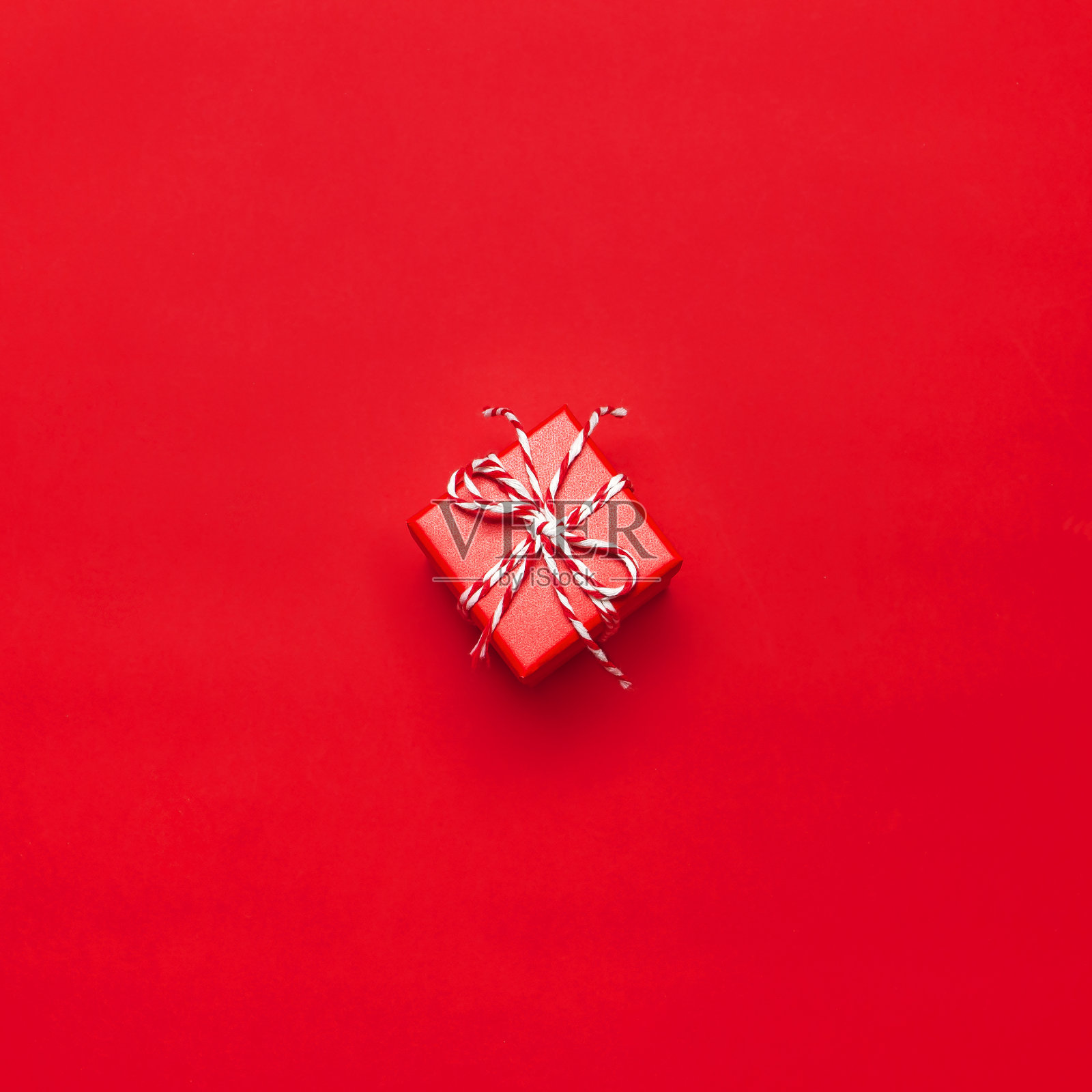 一个红色的礼品盒装饰花边在红色的背景顶视图平面铺设。节日概念新年或圣诞礼盒礼物圣诞假期。祝贺文本背景空间照片摄影图片