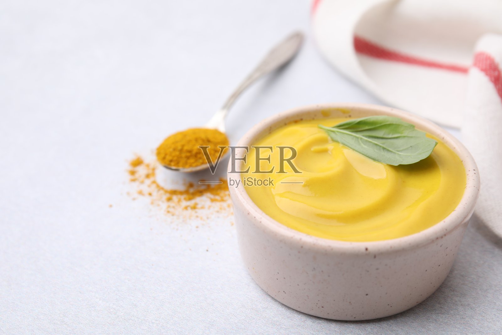 美味的咖喱酱、粉和罗勒叶放在浅色的桌子上，特写。文本空间照片摄影图片