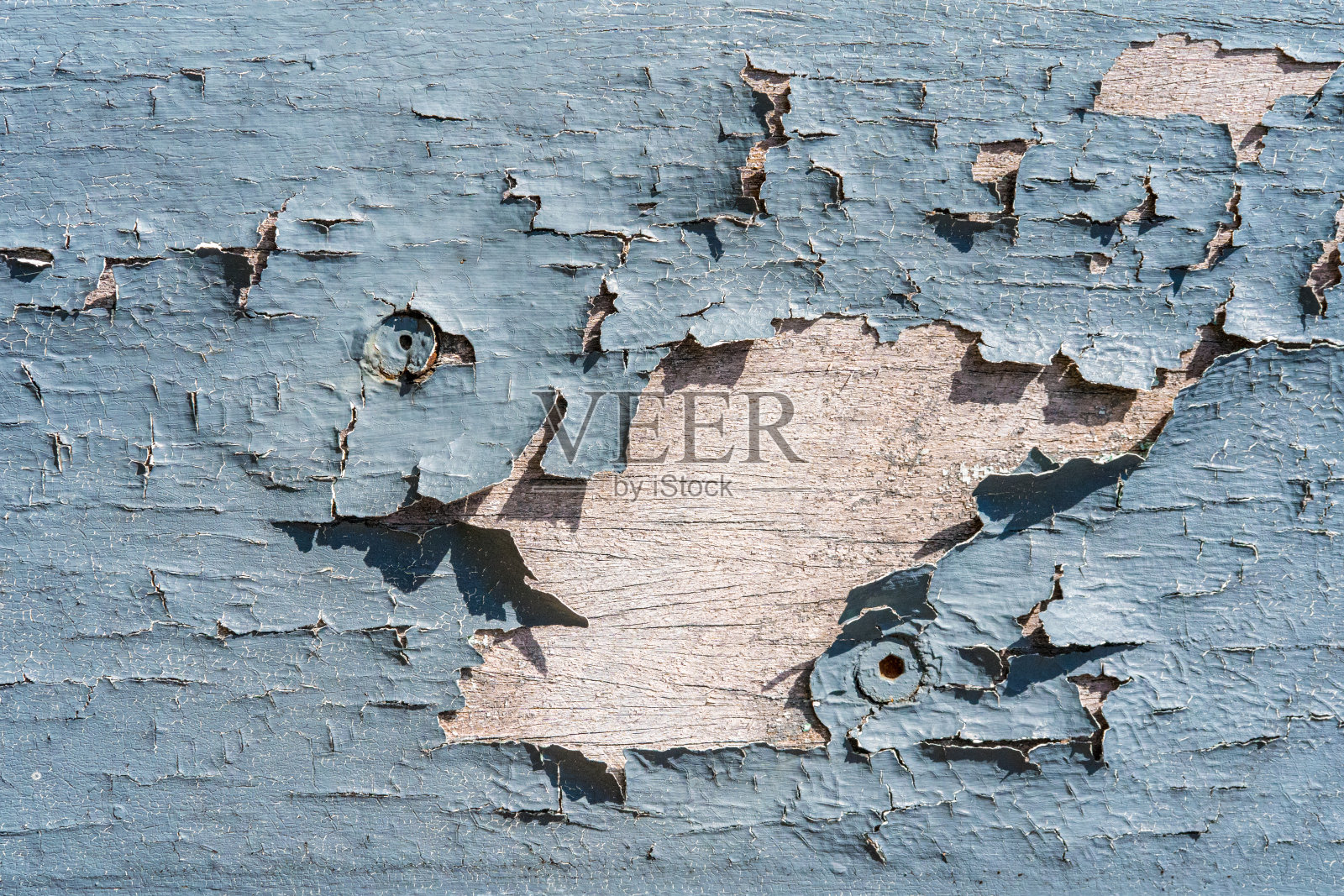 用螺栓和螺丝在木板上涂上旧的剥落和风化的蓝色油漆照片摄影图片