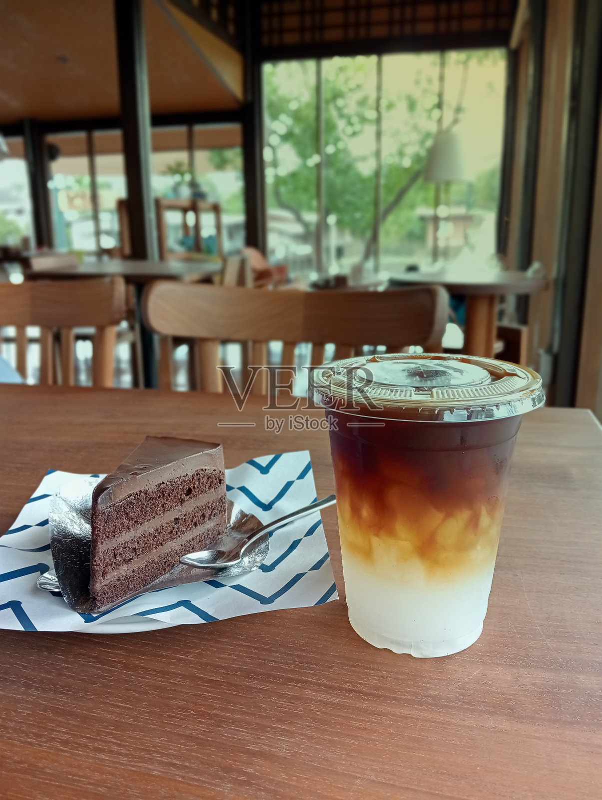 冰椰子美式咖啡和一块美味的巧克力蛋糕放在木桌子上照片摄影图片