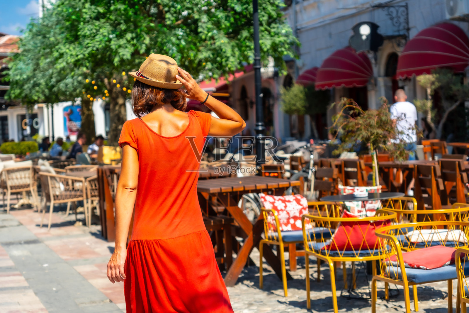 穿着红色衣服和帽子的旅游妇女在Shkoder市的街道上享受假期。阿尔巴尼亚照片摄影图片