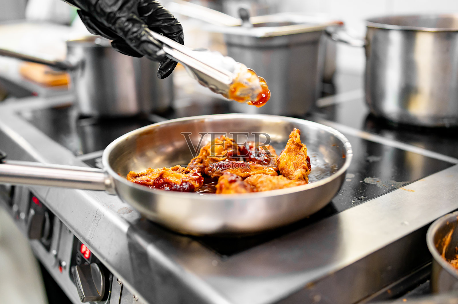 厨师在厨房的平底锅上用酱汁煮鸡翅照片摄影图片