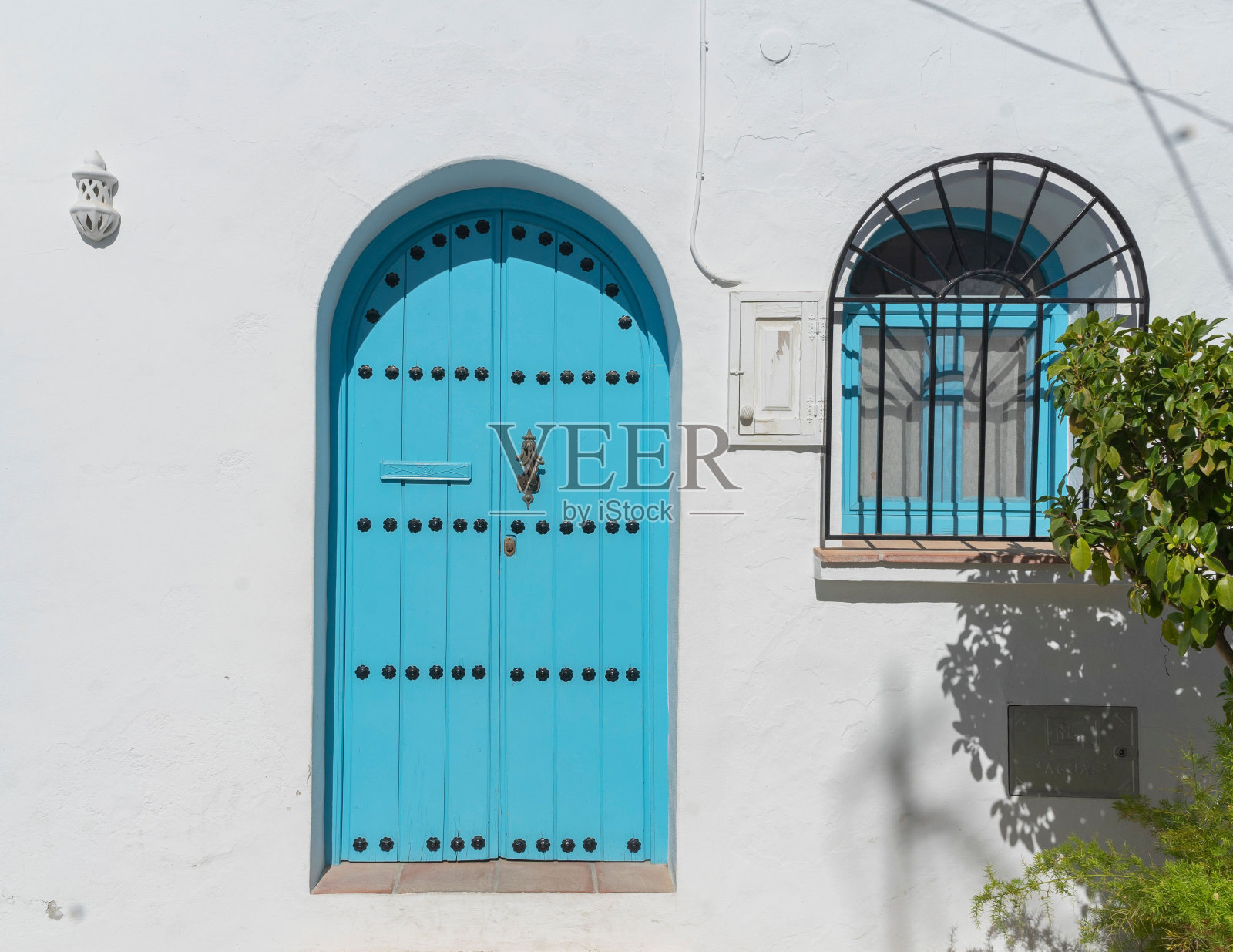 白色背景或墙壁上的古色古香的蓝色木门和黑色铁条的蓝色窗户照片摄影图片