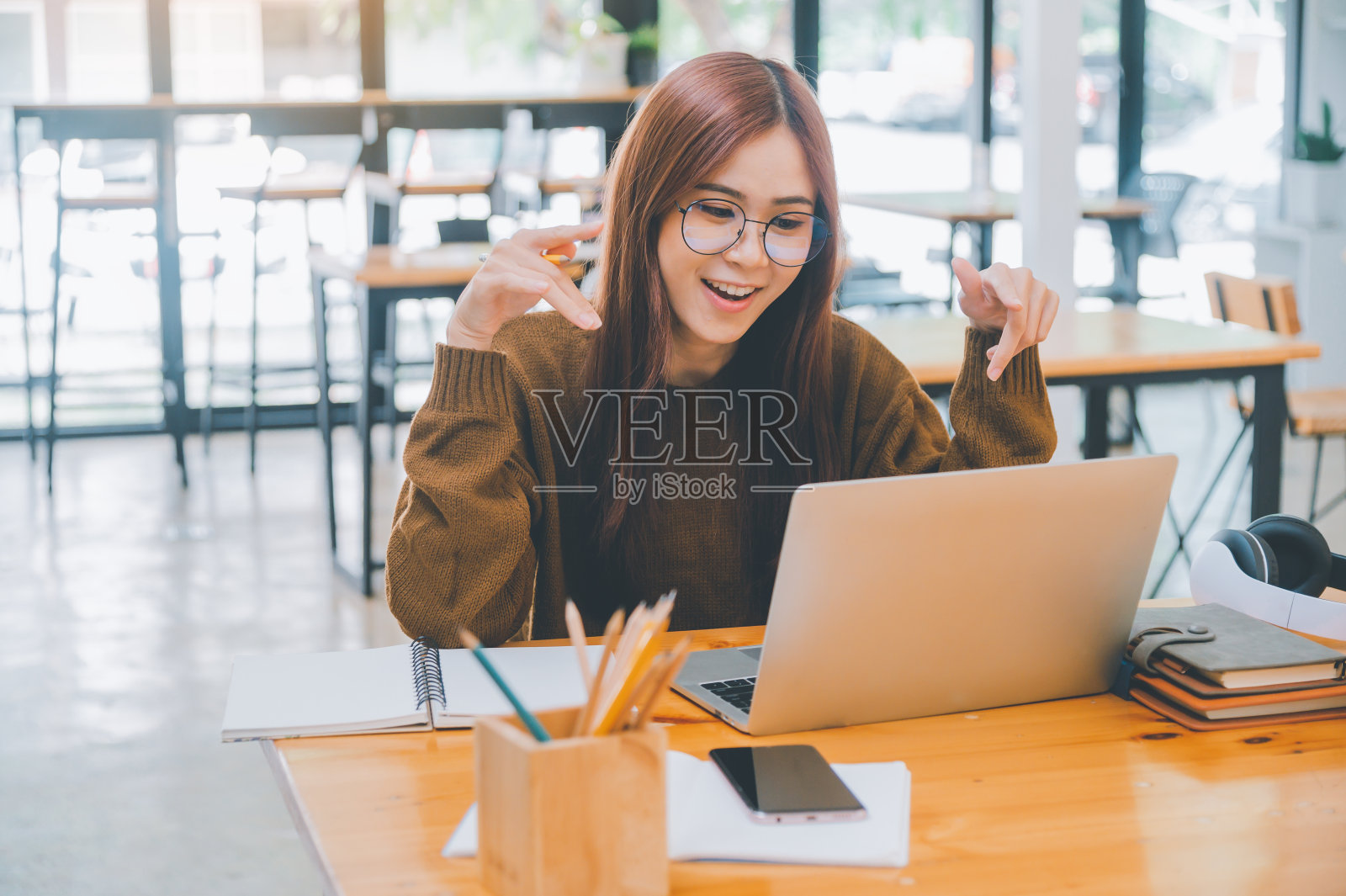 戴着耳机的年轻学生在线学习，远程学习，并了解全球冠状病毒大流行的最新情况。照片摄影图片