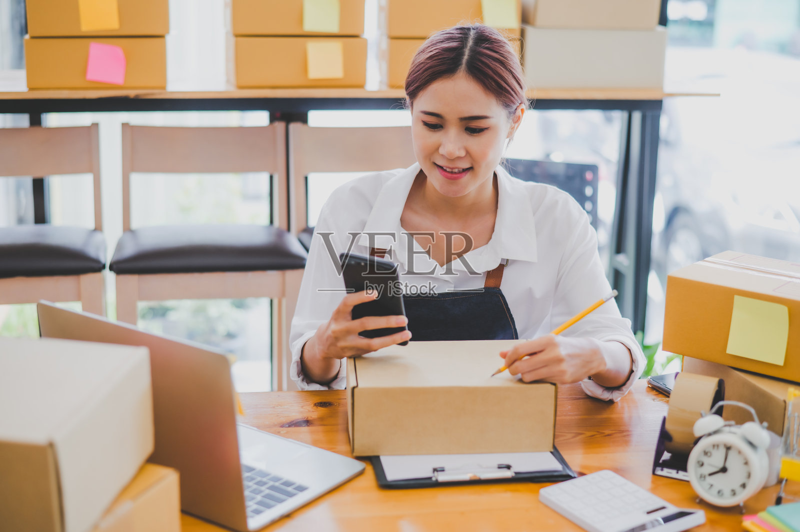 小企业主在网上写下他们的名字和地址，把产品和产品送到他们的客户手中。并检查客户在网上零售商订购的订单-网上购物照片摄影图片