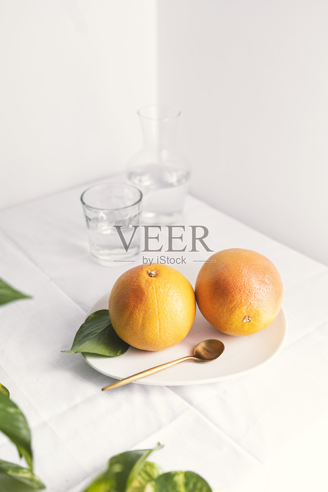 葡萄柚放在盘子里，配上金勺子，白色背景，留出文字空间。照片摄影图片