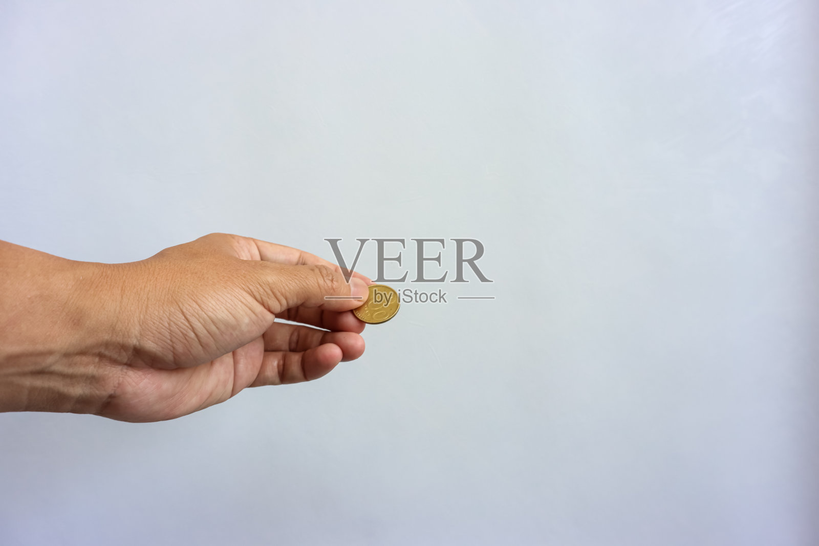 人的手拿印尼盾硬币孤立在白色背景。收集、储蓄、投资或捐赠的概念照片摄影图片