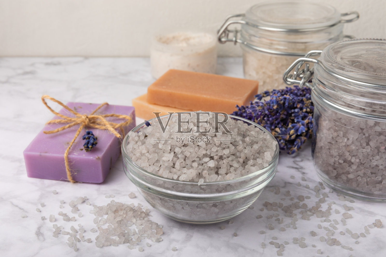 薰衣草温泉。海盐、薰衣草花、芳香蜡烛、身体乳和手工香皂。天然草药化妆品与薰衣草花大理石背景。放松的概念。美容。副本的空间。照片摄影图片