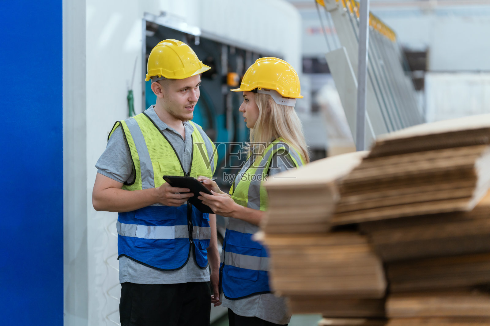 男技术人员和女技术人员正在仓库里检查机器。大量纸板箱男技术人员和女技术人员正在仓库检查机器。大量纸板箱库存照片摄影图片