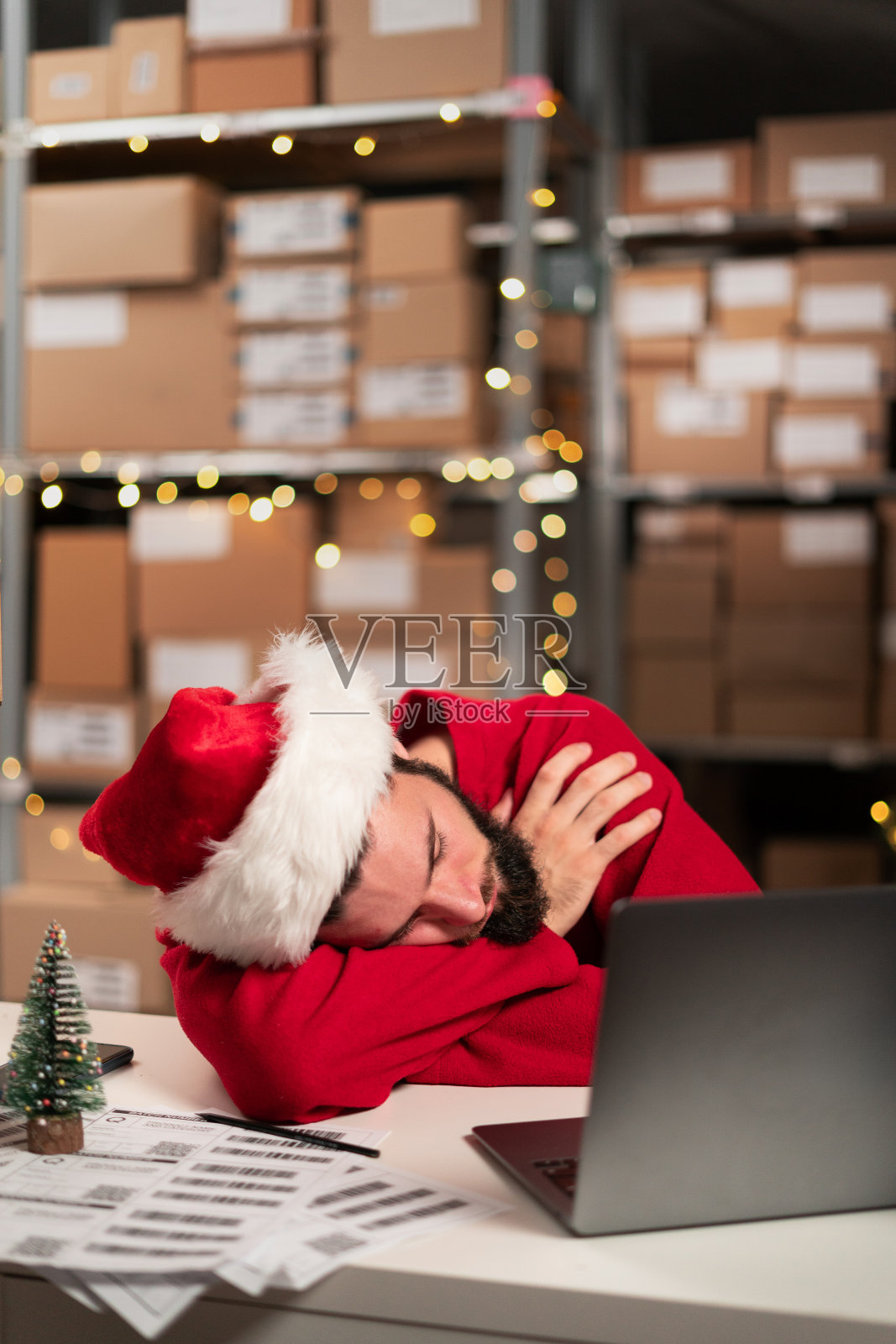 年轻的仓库工人在平安夜加班后睡得很累照片摄影图片