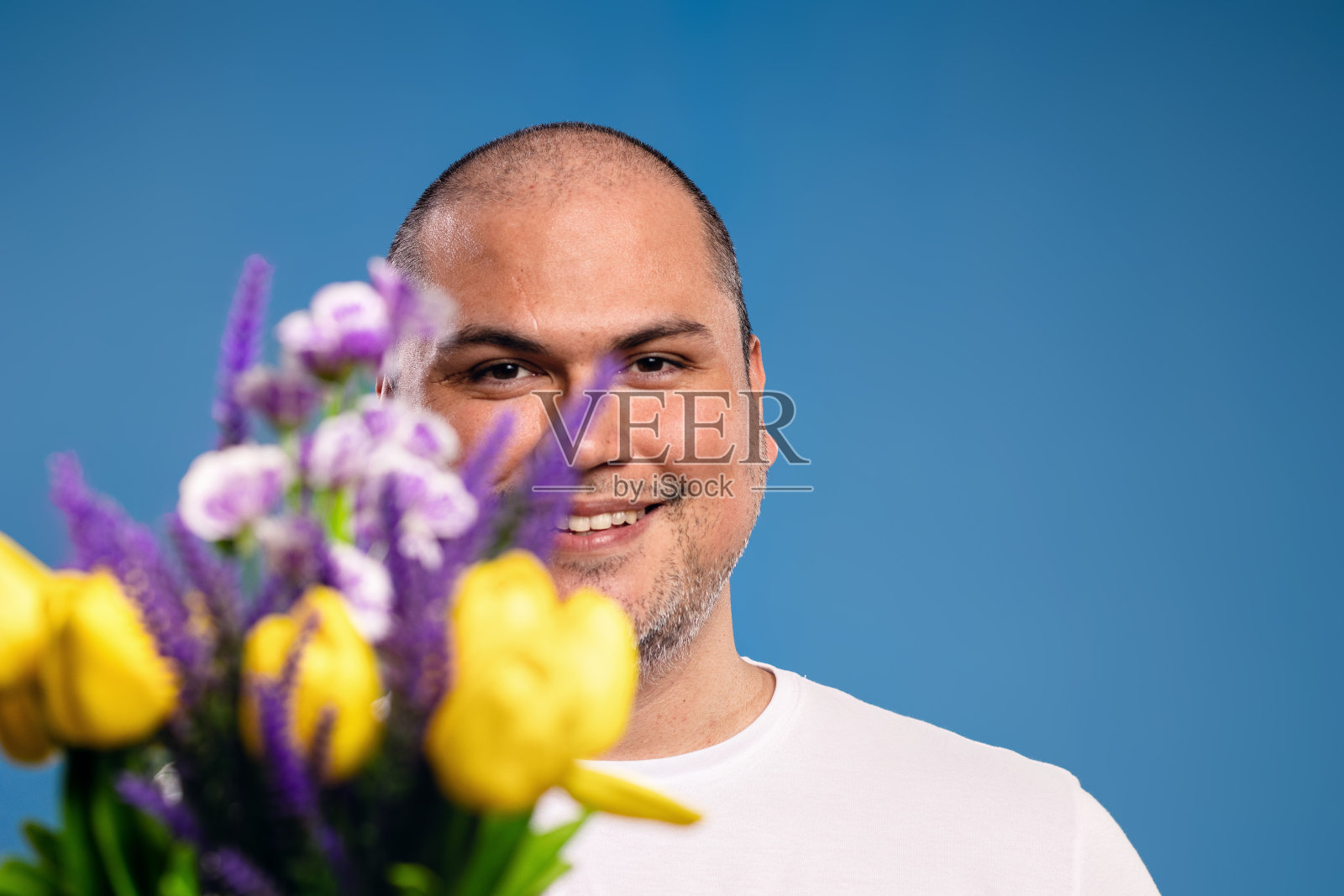 一名男子手持花束，与下巴齐平照片摄影图片