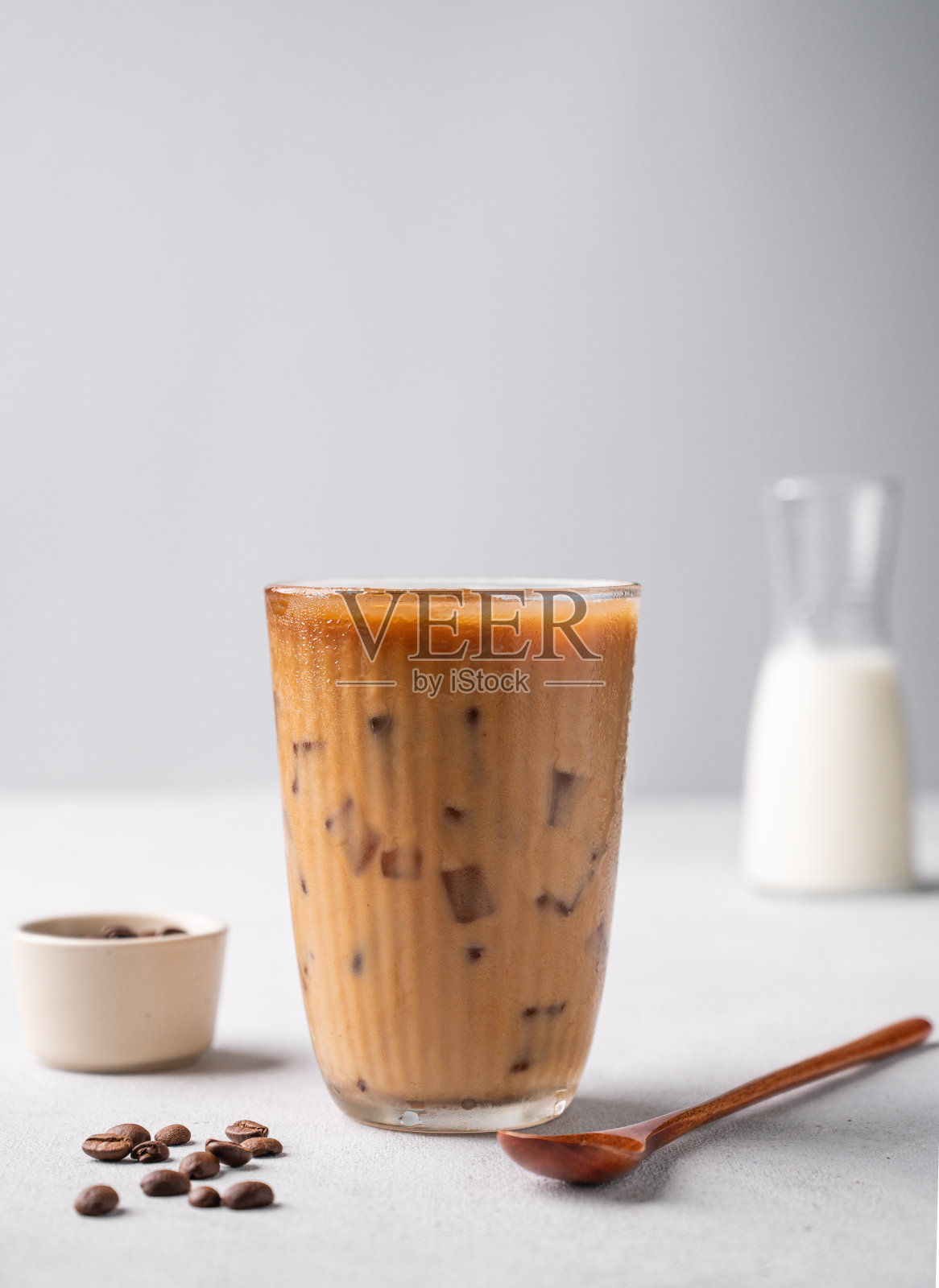 纯素冰咖啡拿铁，高杯，豆浆，浅色背景，豆子和勺子。夏日小点心精酿饮品概念。照片摄影图片