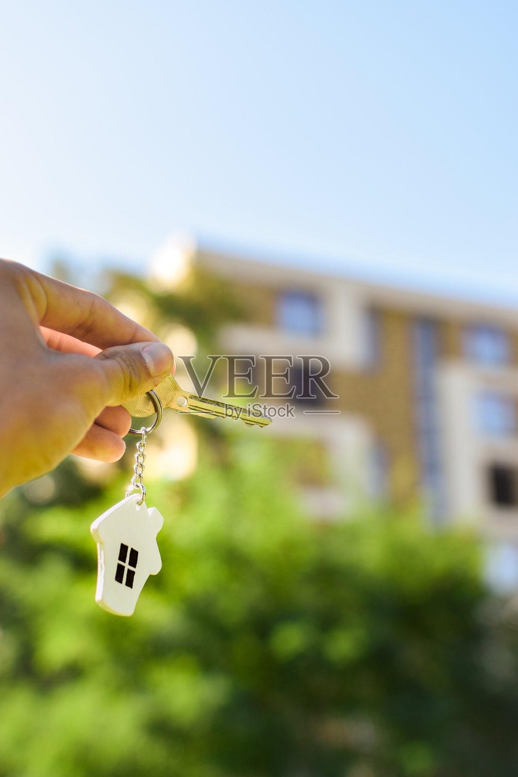 手持钥匙与房屋挂件。照片摄影图片