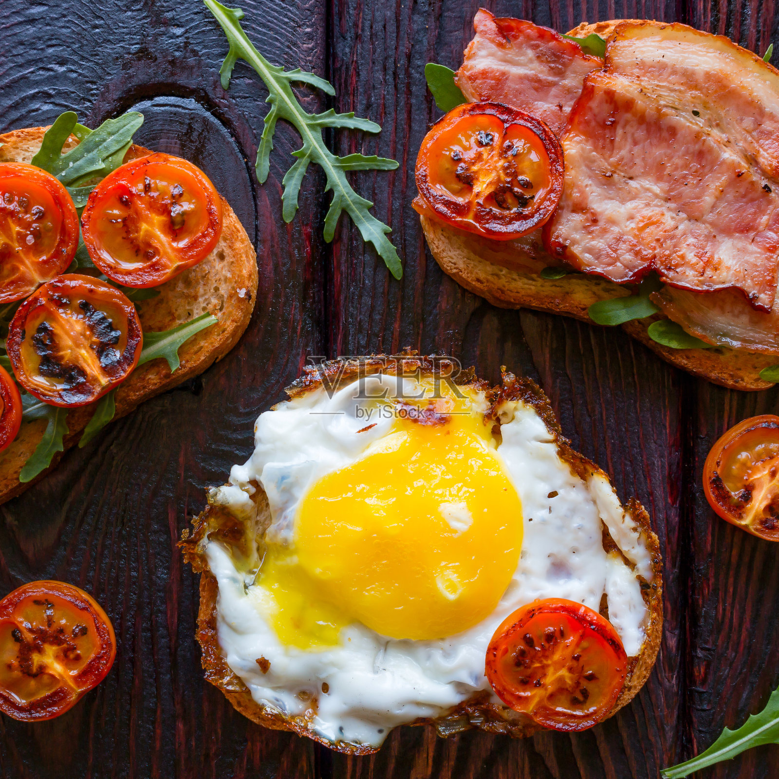 美味的三明治放在黑色背景上，用烤西红柿和芝麻菜装饰照片摄影图片