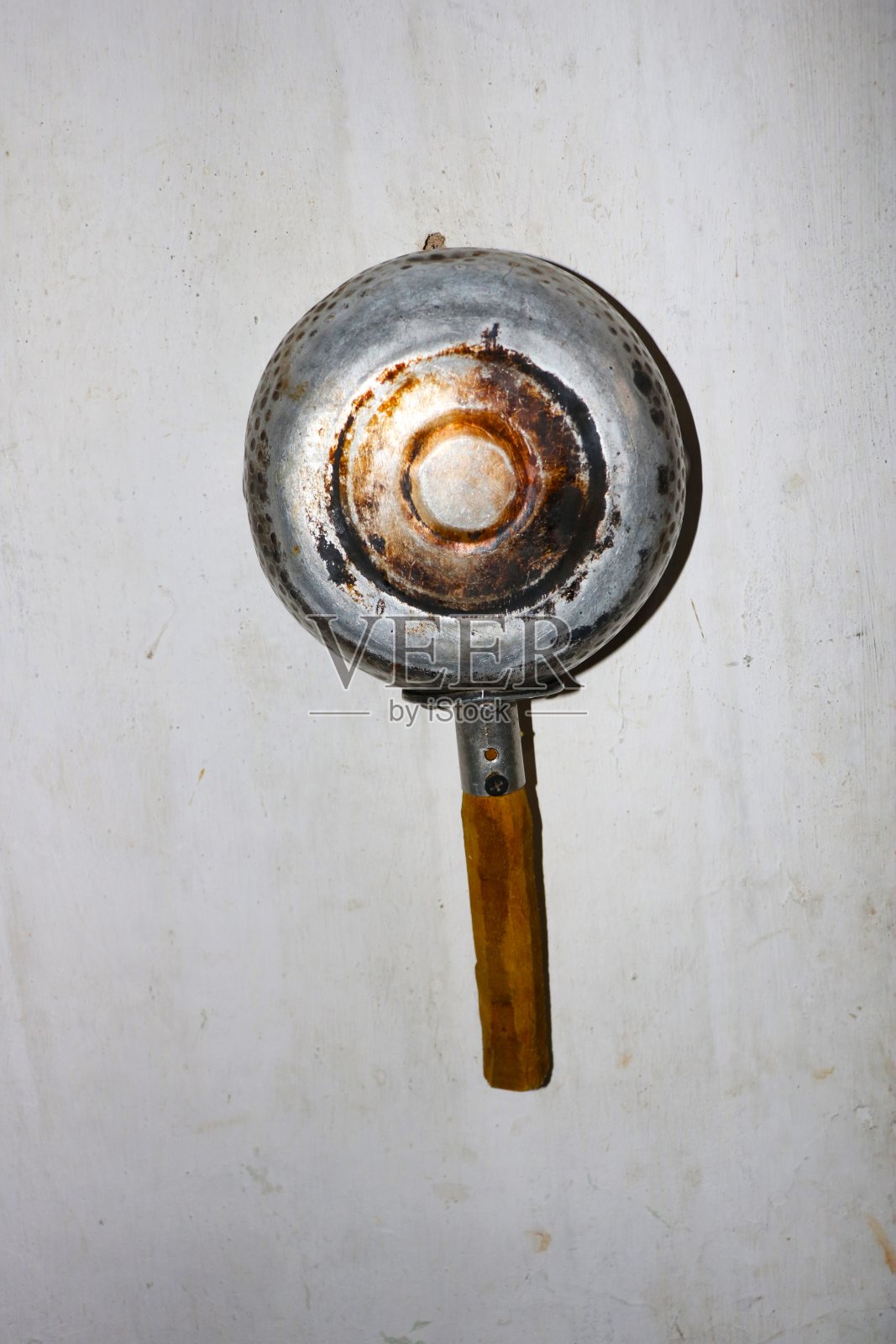 木柄平底锅挂在墙上。旧木柄平底锅。照片摄影图片