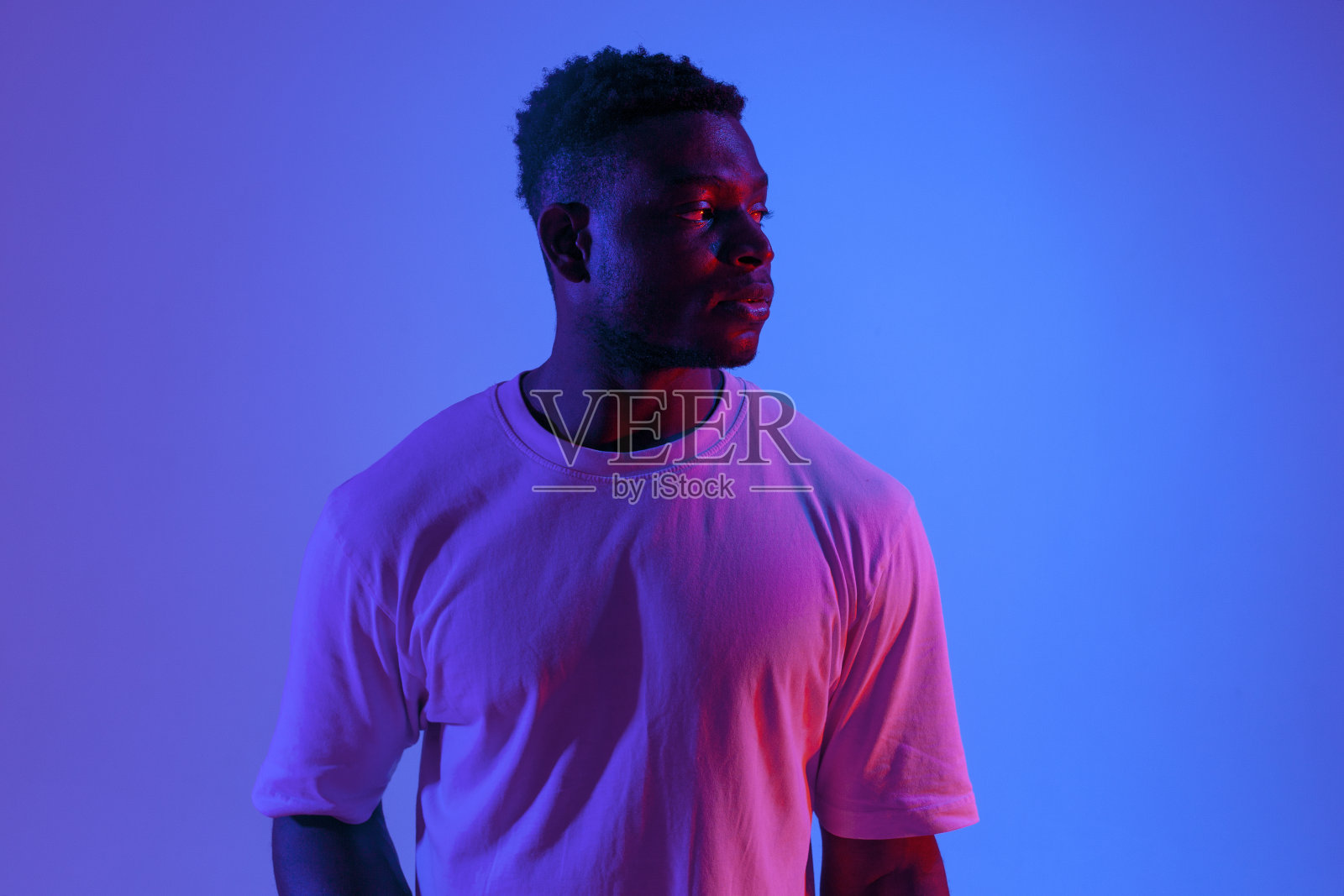 严肃的非裔美国人在霓虹灯下看向别处，红蓝灯光下的人像照片摄影图片