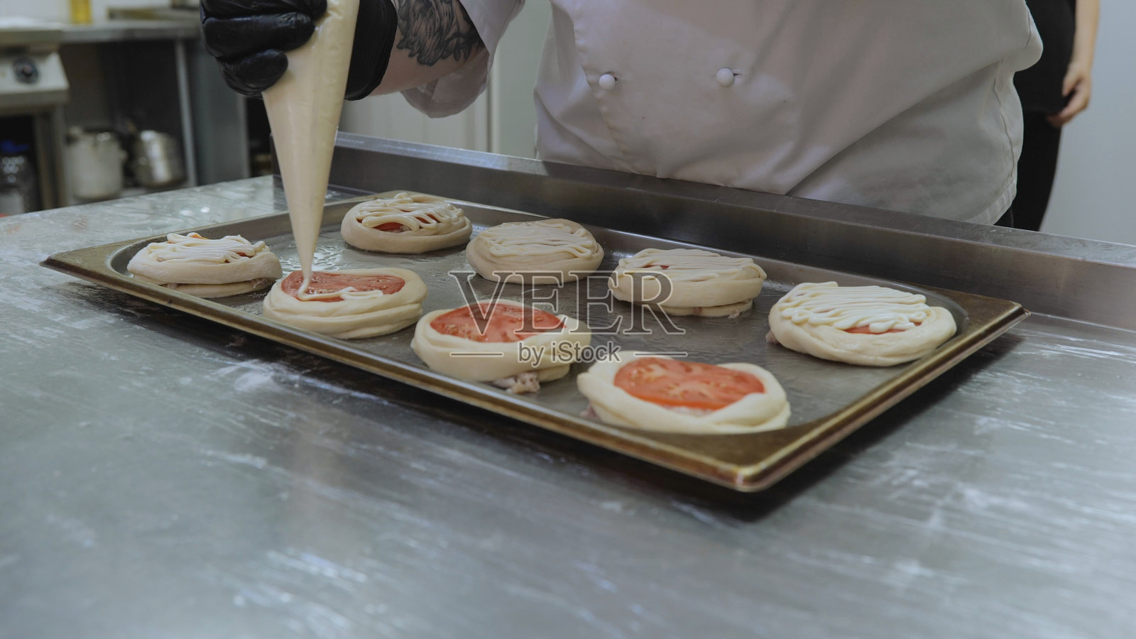 专业厨师准备糕点。面包师用肉末和番茄准备糕点，厨师在厨房准备糕点，厨师的手准备糕点的特写照片摄影图片
