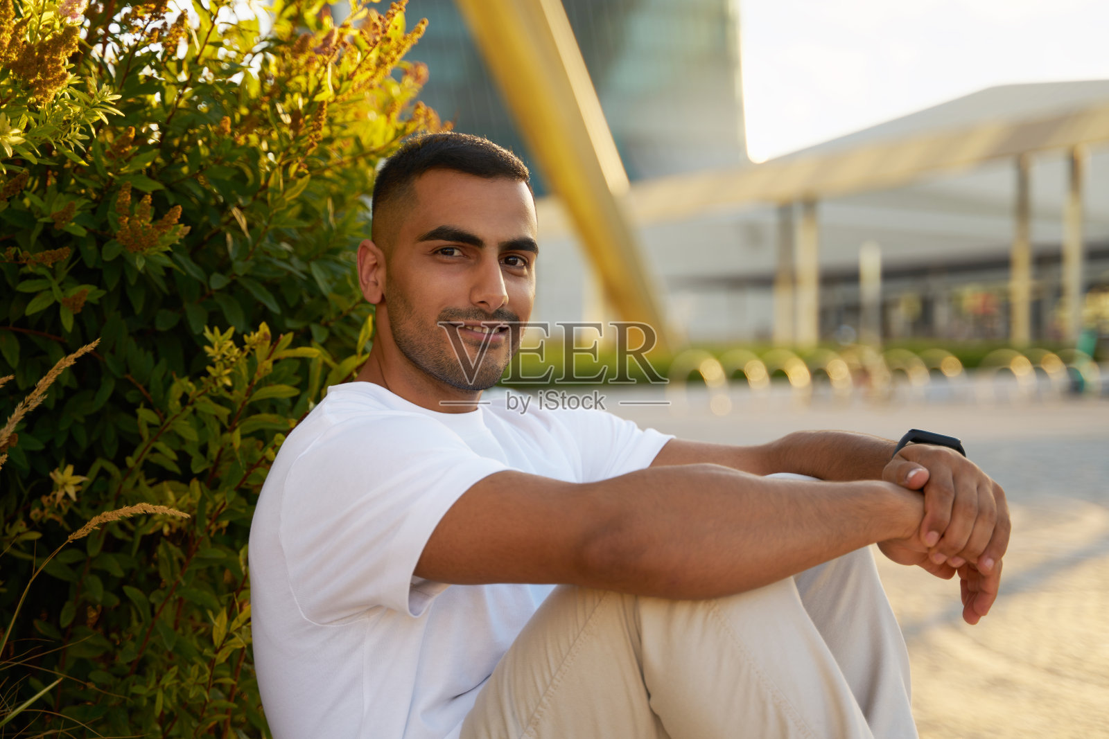 穿着白色T恤的迷人伊朗男人在公园里放松，看着镜头照片摄影图片