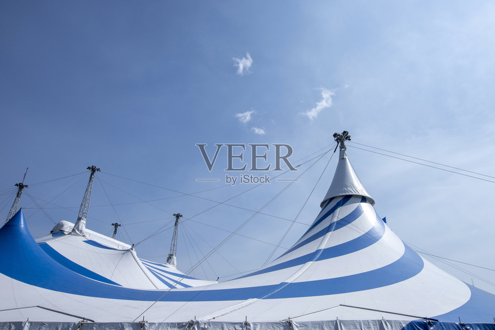 阳光明媚的天空下，蓝色和白色的大马戏团帐篷照片摄影图片