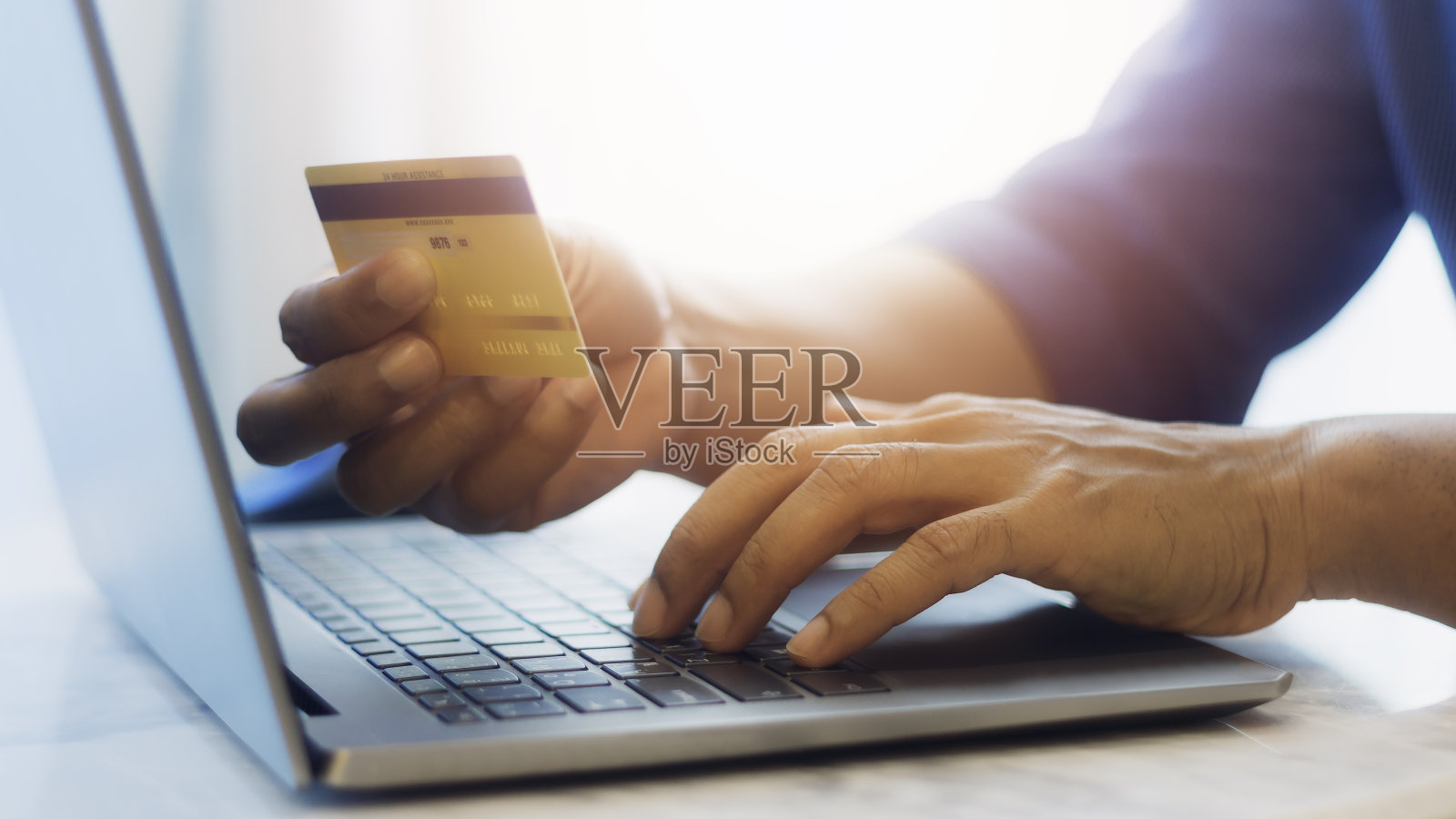 手持信用卡和使用笔记本电脑。数字货币转账、银行和电子商务概念。照片摄影图片