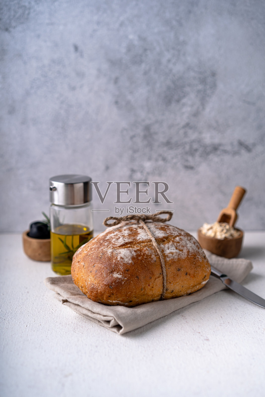 在一张白色抽象的桌子上，新鲜出炉的酸面包加橄榄和迷迭香。工匠面包照片摄影图片