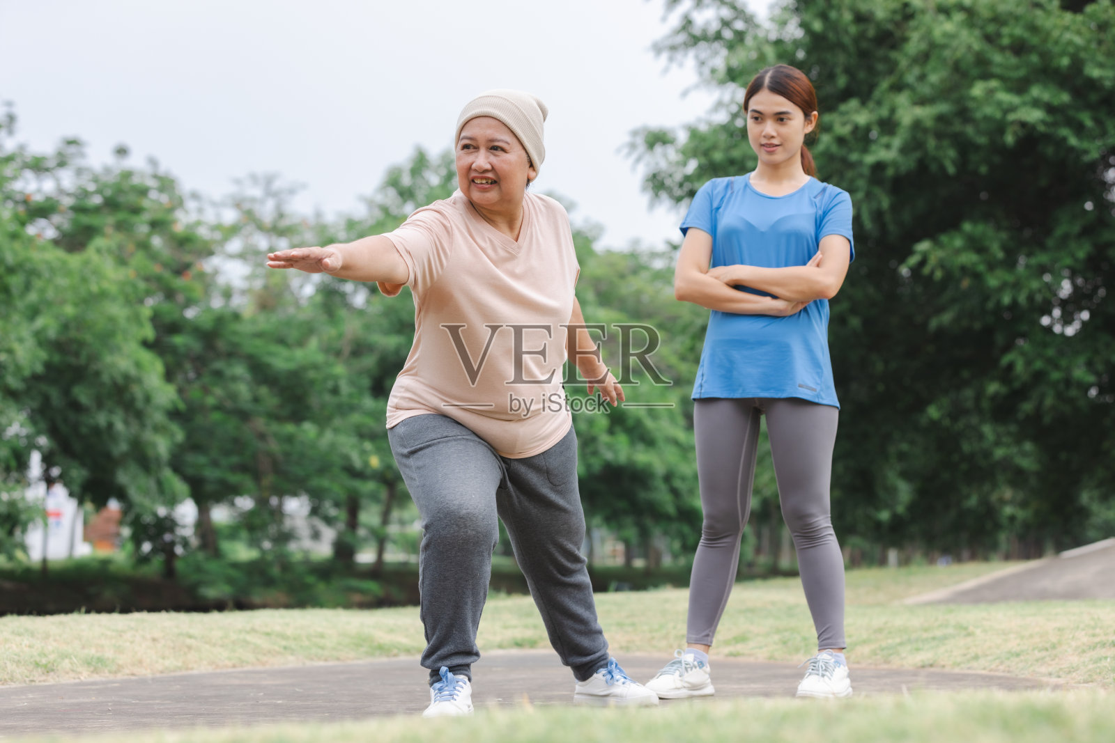 高级亚洲人与教练在家里的公园里做运动。健康生活理念。照片摄影图片