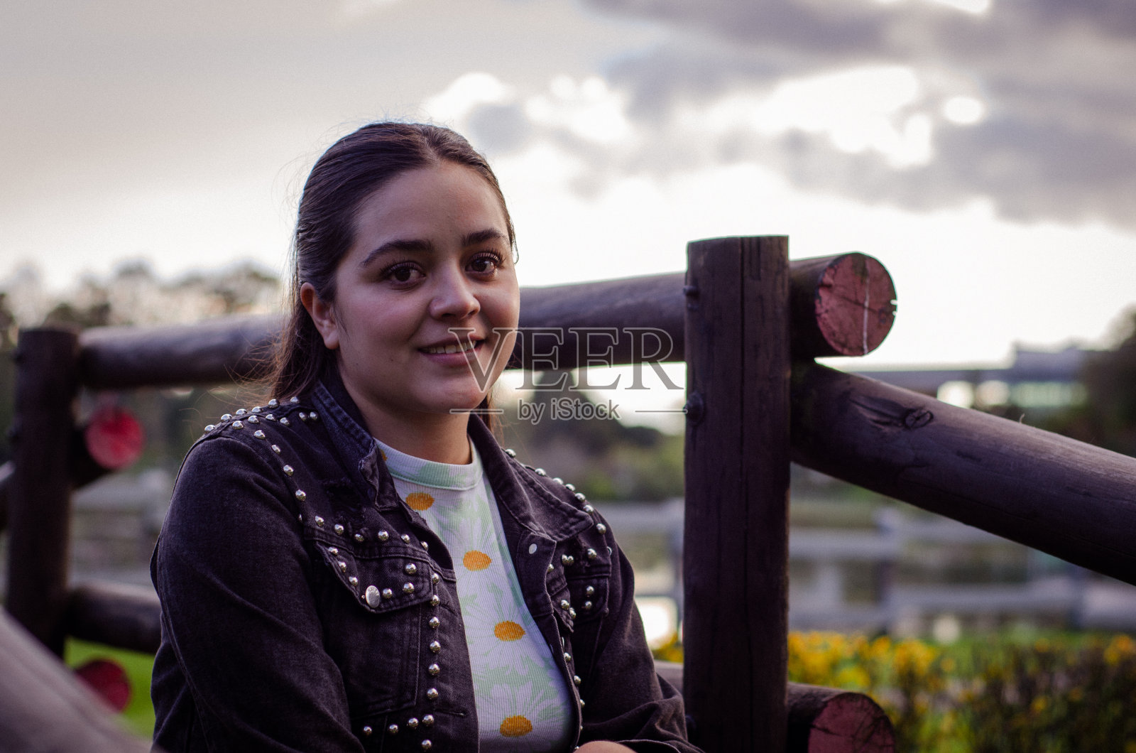 日落时分，美丽的女人坐在公园里微笑照片摄影图片