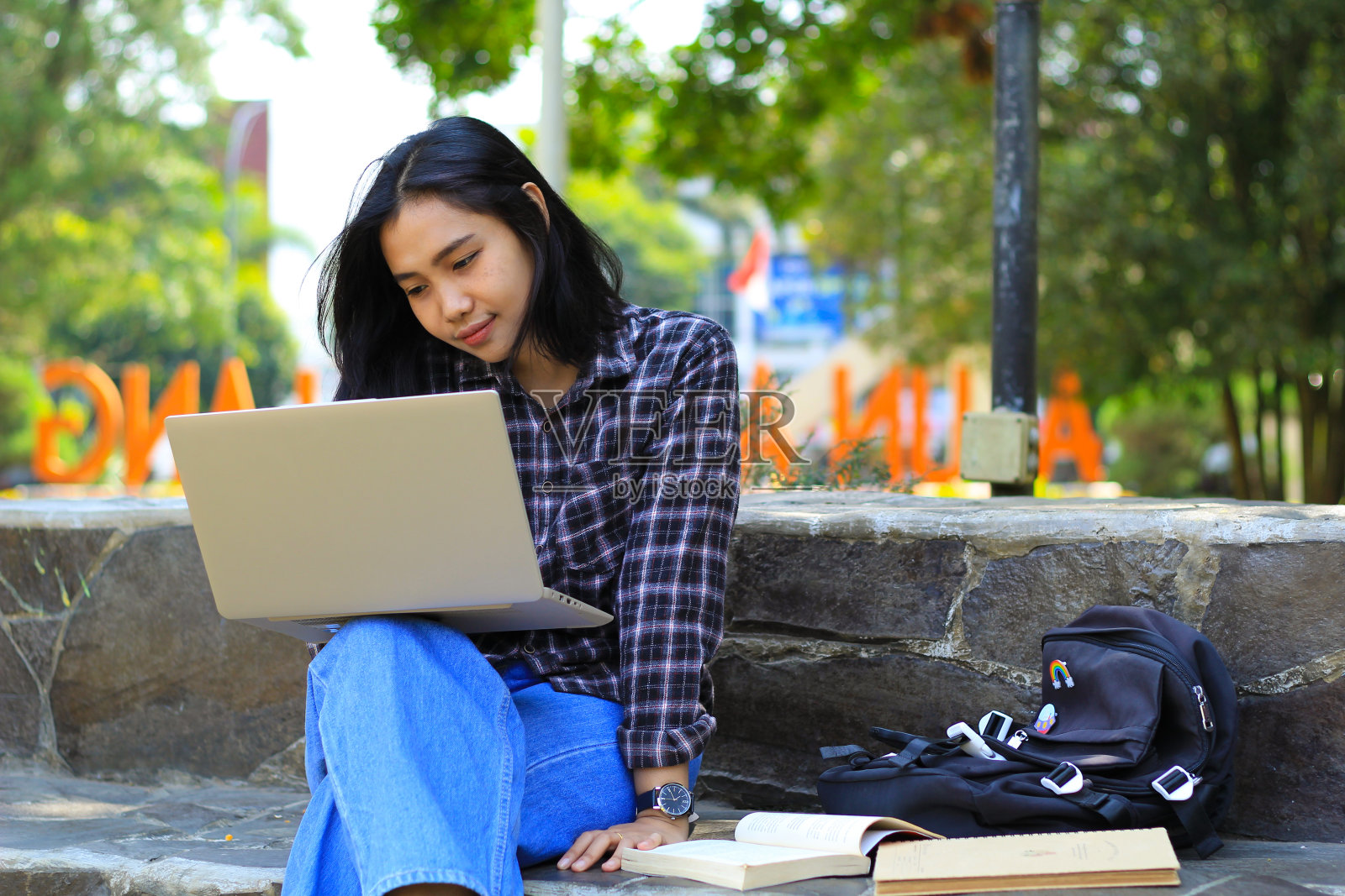 年轻微笑的亚洲妇女使用笔记本电脑和写笔记本，快乐的亚洲学生观看网络研讨会和学习课程照片摄影图片
