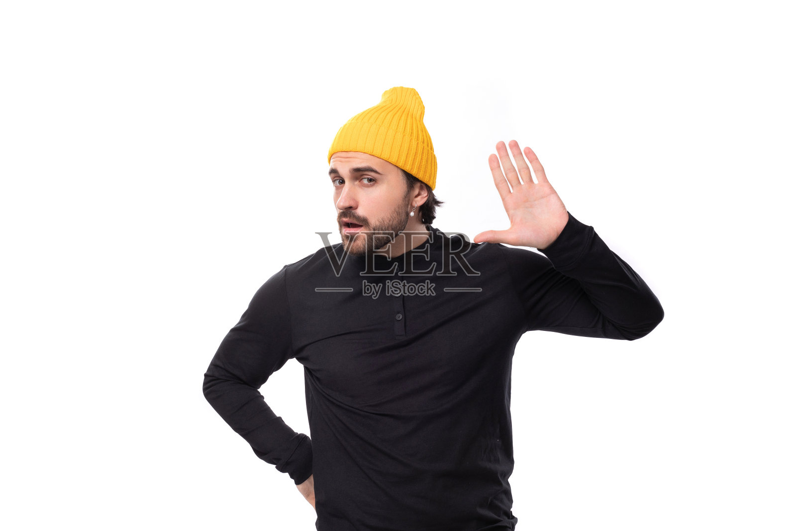 穿着黑色夹克，头戴黄色帽子的年轻的野蛮男模特惊讶地望向别处照片摄影图片