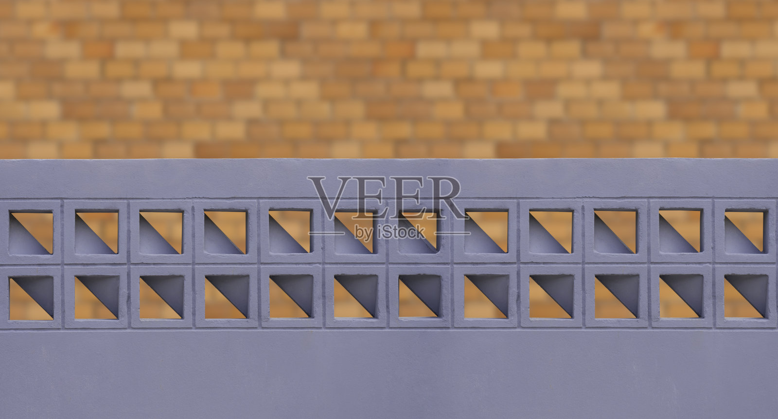 灰色的混凝土栅栏墙与通风块的几何图案在模糊的砖房墙背景前面照片摄影图片