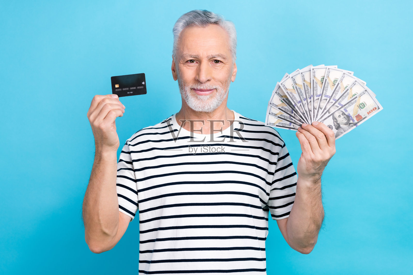 照片肖像英俊的爷爷拿着钱迷美元信用卡穿着时髦的条纹衣服孤立在蓝色的背景照片摄影图片
