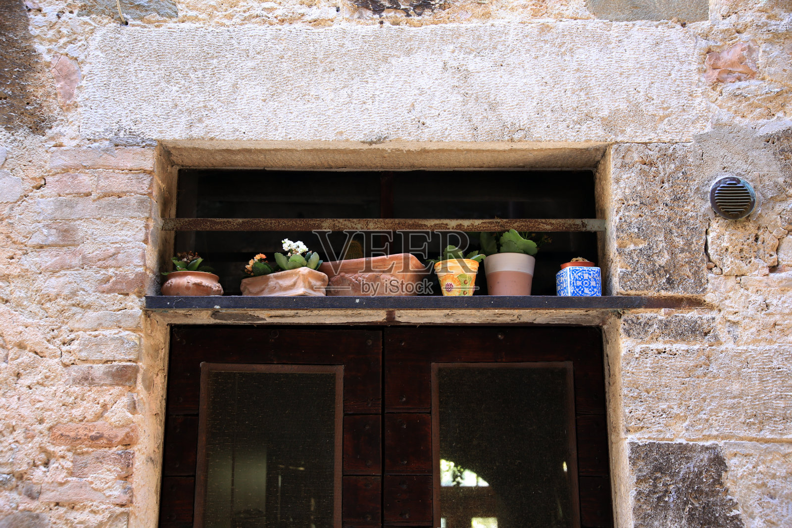 旧门上方石墙上的壁龛，装饰着盆栽植物，意大利翁布里亚照片摄影图片
