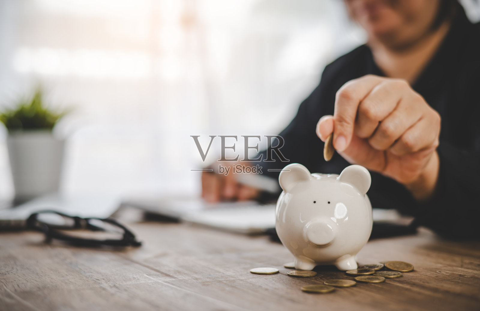 手拿硬币与猪存钱罐。储蓄和财务账户的概念照片摄影图片