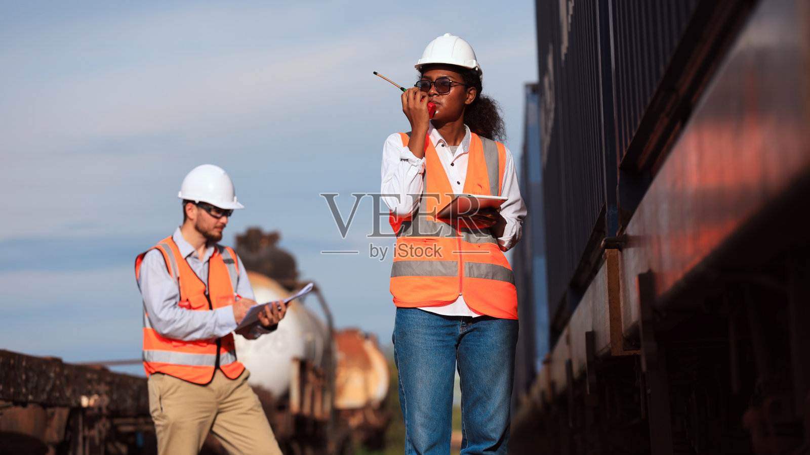 一组后勤工程师和一名技术人员，以及一名货运列车维修专家在铁路货场工作并讨论货物集装箱的安排照片摄影图片