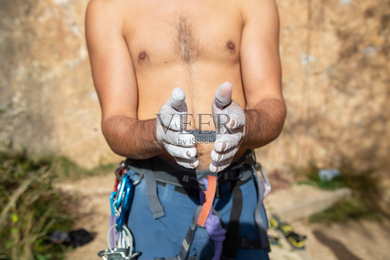 一名无脸赤裸的男子戴着登山装备，双手沾着白色氧化镁粉，站在户外拍手照片摄影图片