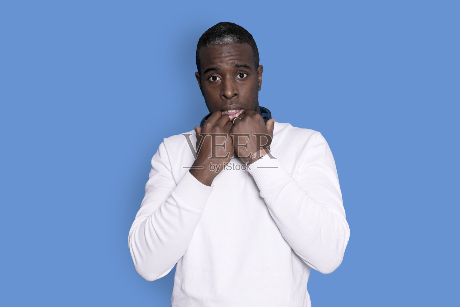 年轻英俊的男子身穿蓝底白毛衣，捂着嘴，惊讶地看着镜头，不敢相信意想不到的谣言。照片摄影图片