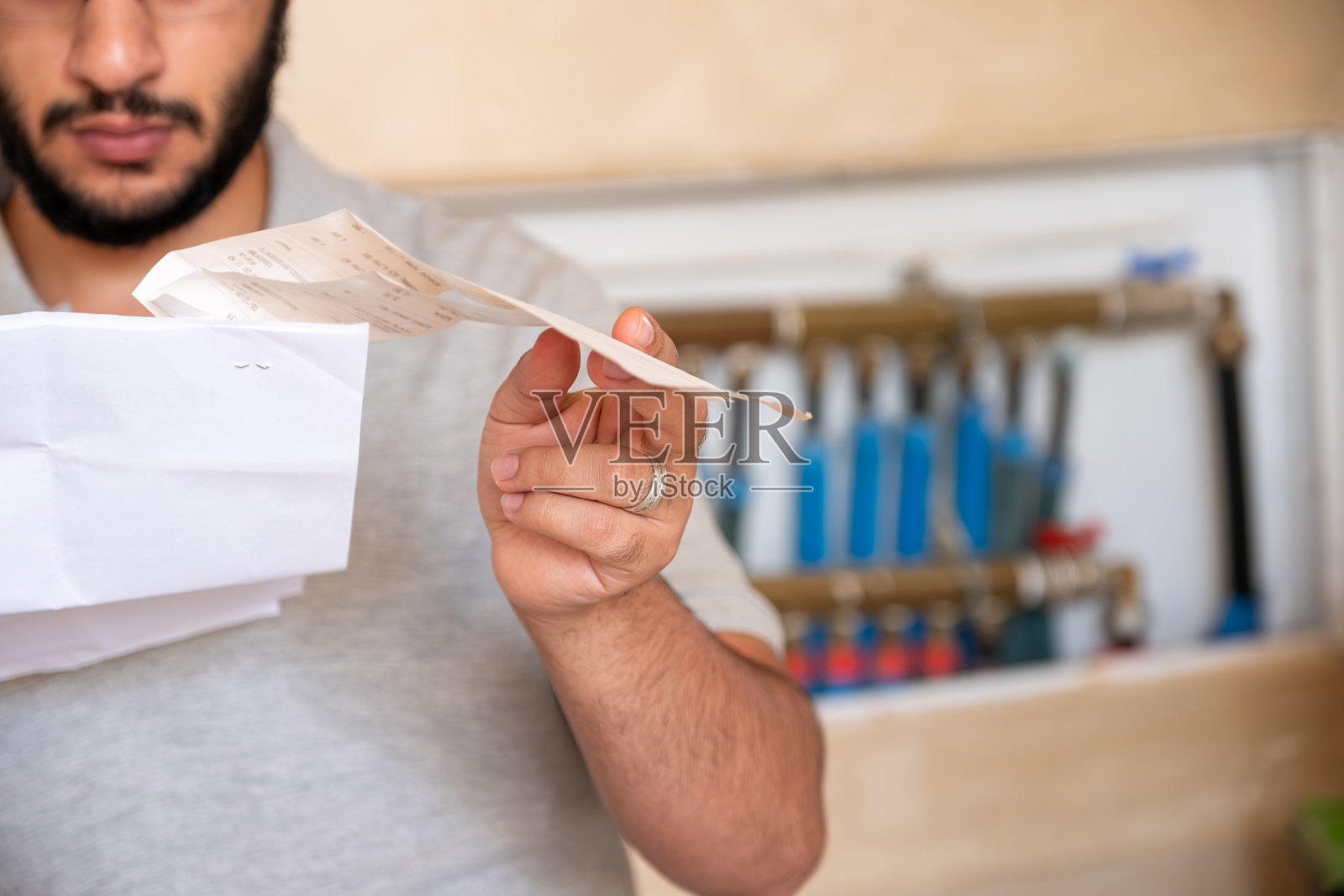 男人拿着维修账单，背景是管道照片摄影图片