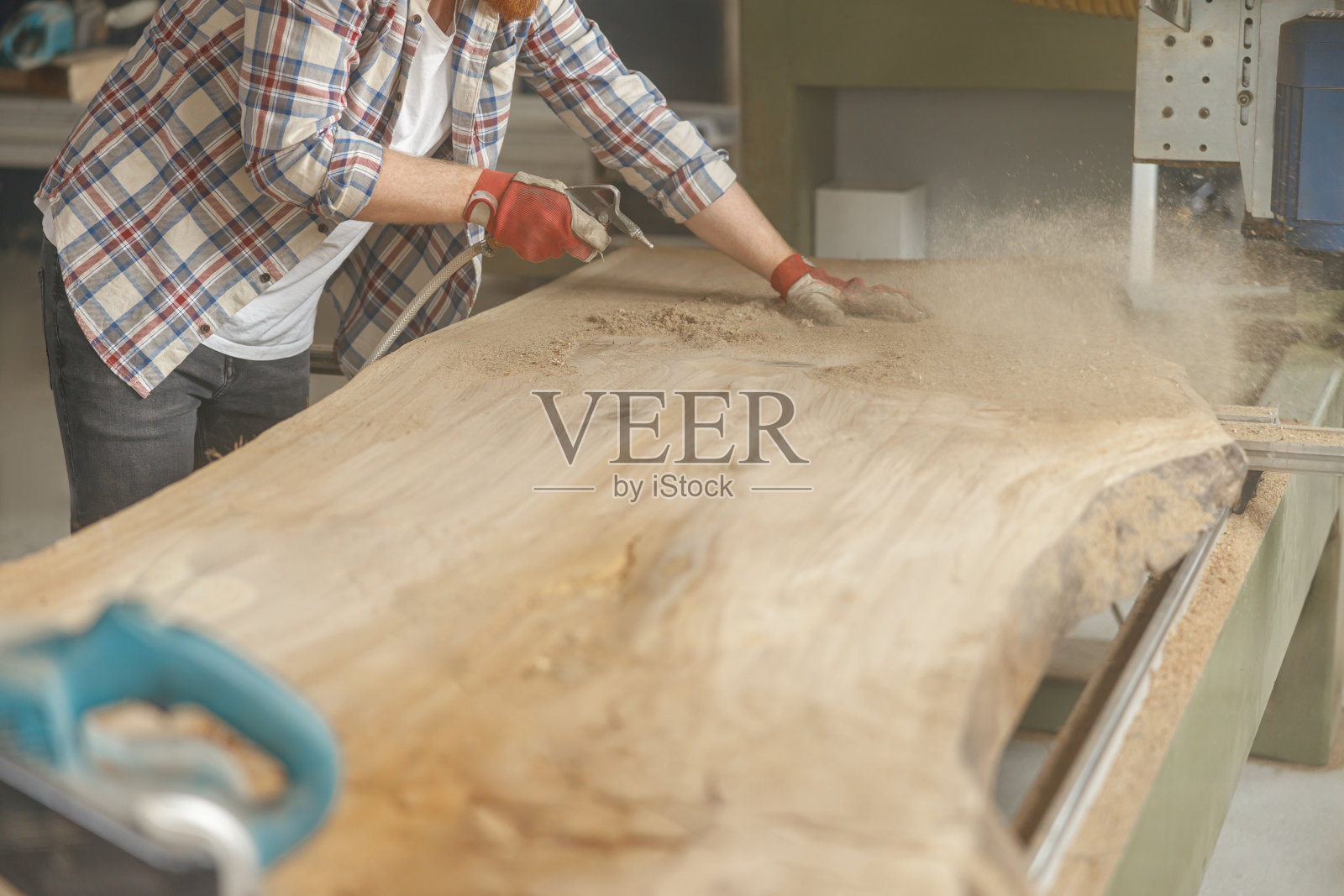 木工车间的木工正在用空气压缩机清理锯末照片摄影图片