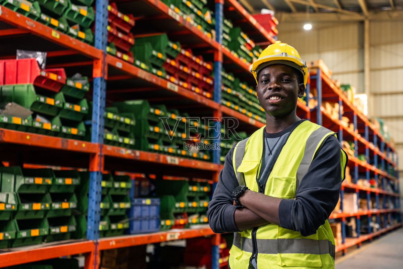 在工厂仓库工作的非洲男性工业工人的肖像。有魅力的男性工业工程师独自在制造工厂处理订单和产品，然后微笑着看着镜头。照片摄影图片