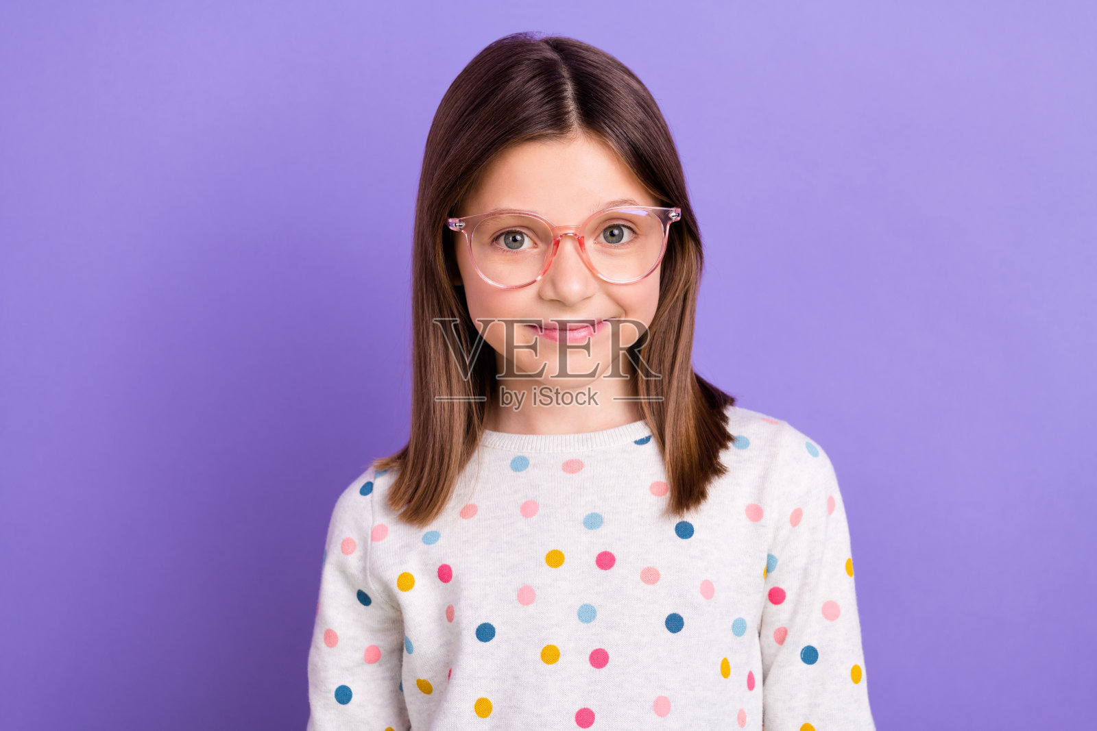 照片中闪亮迷人的小女孩穿着带点的套头衫眼镜微笑着孤立的紫色背景照片摄影图片