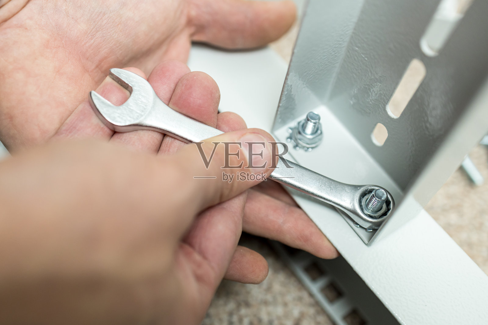 他手里的扳手拧紧了金属结构上的螺母照片摄影图片