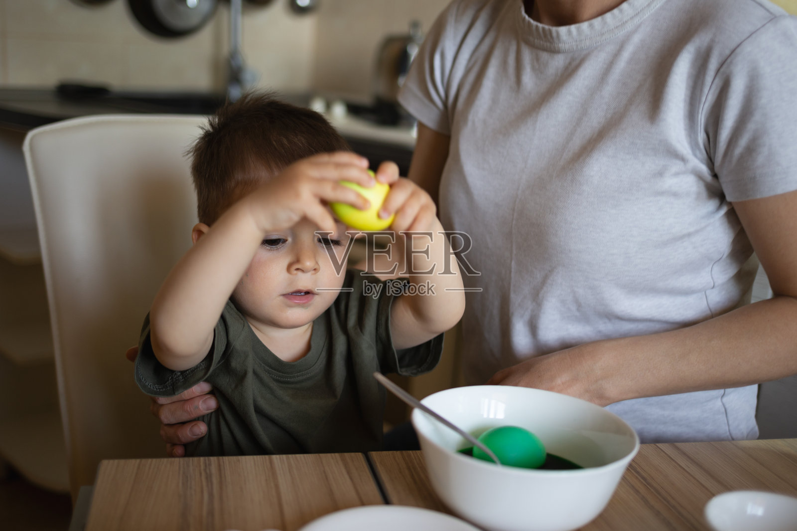 可爱的小男孩和妈妈在厨房的桌旁画复活节彩蛋照片摄影图片