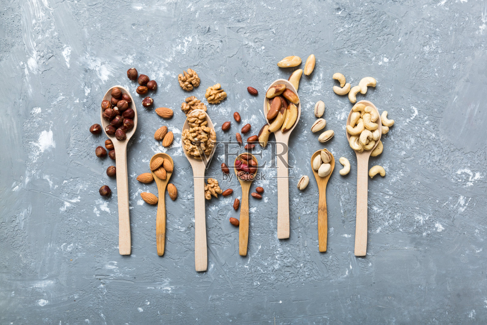 用白色木勺混合坚果。在彩色背景上混合各种坚果。开心果、腰果、核桃、榛子、花生和巴西坚果照片摄影图片