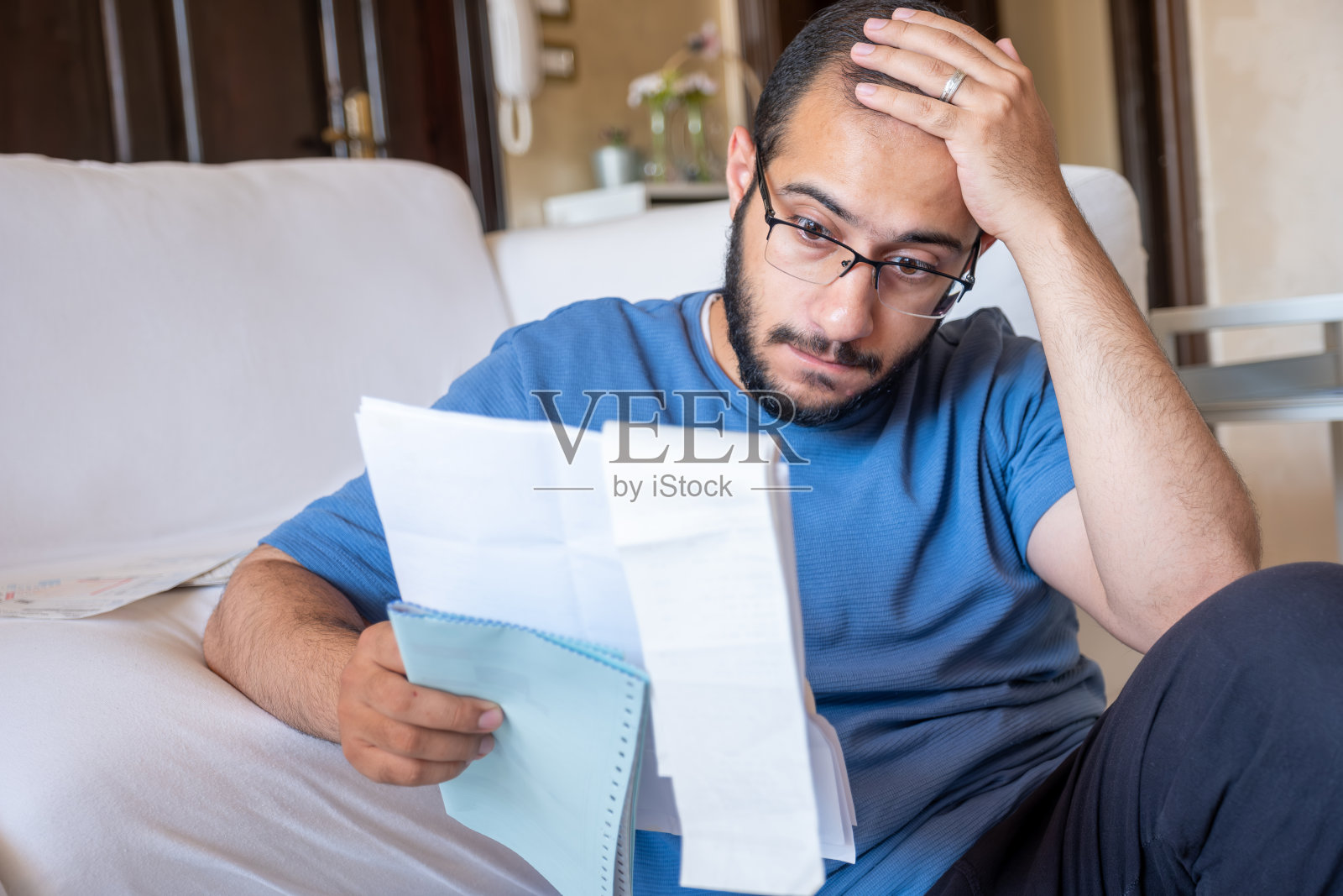 年轻男人坐在客厅里核对收据，用计算器计算生活费用照片摄影图片