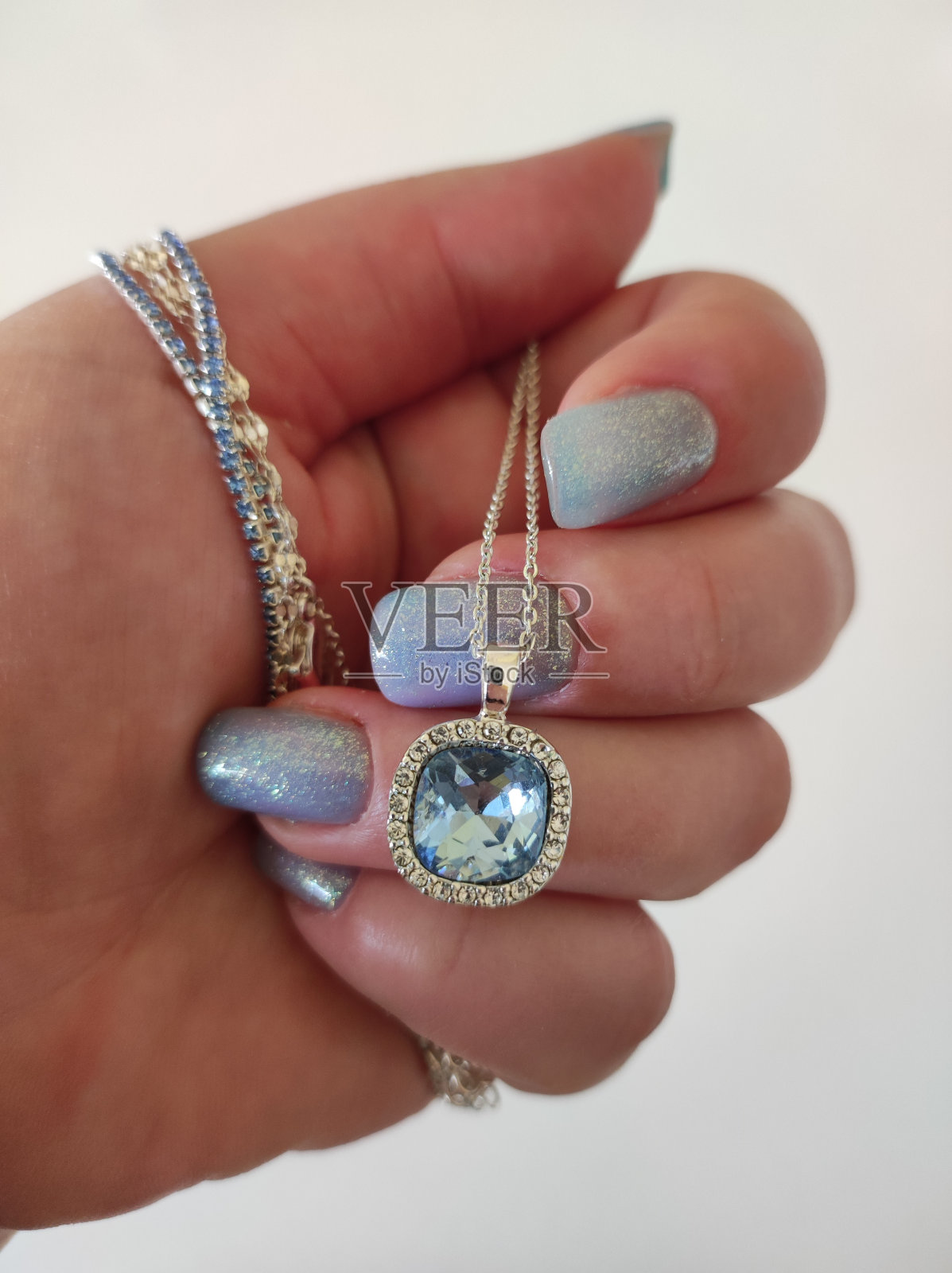 女性手与蓝色指甲拿项链与蓝色宝石照片摄影图片